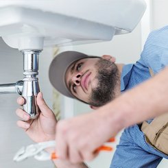 Ein Monteur der unter einem Waschbecken arbeitet