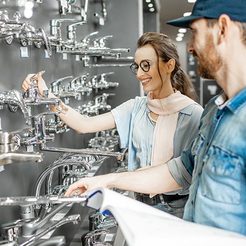 Ein Mann und eine Frau die vor einer Wand mit Sanitaer Armaturen stehen